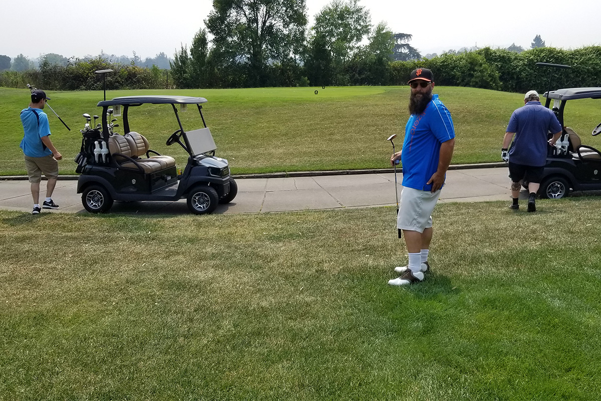 Three people on golf course with carts
